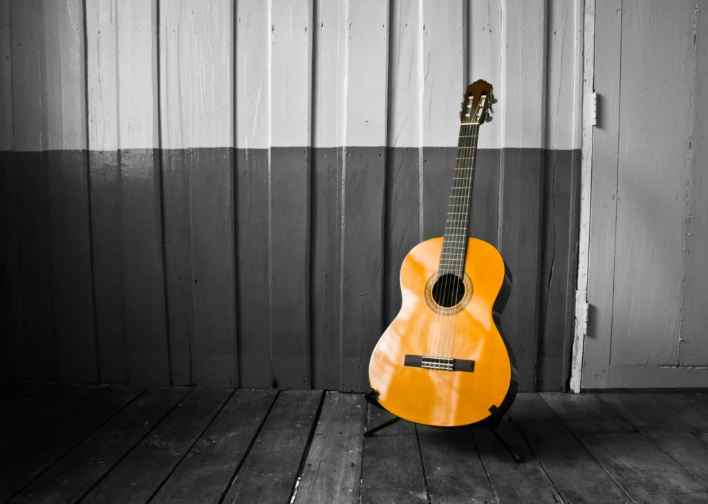 Violão clássico Yamaha C40 encostado em uma parede de madeira, com fundo em preto e branco e o instrumento em destaque colorido.